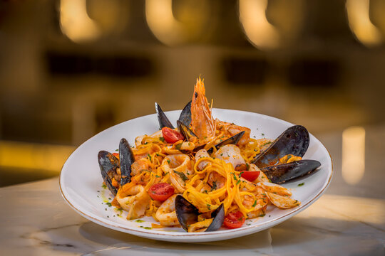 Seafood pasta on a modern bar. Yellow bokeh background 