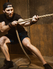 Caucasian strong man pulling rope, cross training gym