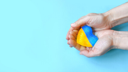 Heart in the colors of the flag of Ukraine in female hands.