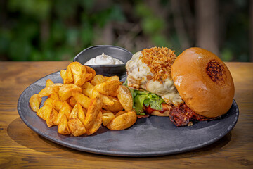 Close-up of home made burger with potatoes on a wooden table