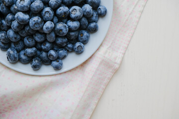 Fresh raw organic blueberries in a plate on a natural linen napkin on the table. Healthy nutrition. Minimalistic simple natural light flat lay template. Superfood. Organic eco health care. Vitamins.