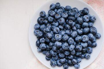 Fresh raw organic blueberries in a plate on a natural linen napkin on the table. Healthy nutrition. Minimalistic simple natural light flat lay template. Superfood. Organic eco health care. Vitamins.