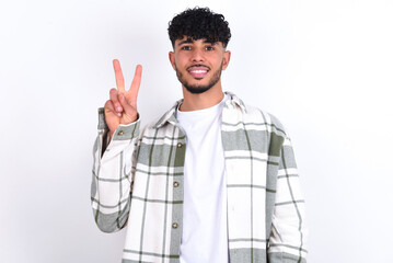 young arab man with curly hair wearing overshirt over white background showing and pointing up with fingers number two while smiling confident and happy.