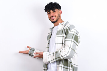 young arab man with curly hair wearing overshirt over white background Inviting to enter smiling natural with open hands. Welcome sign.