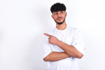 Portrait of young arab man with curly hair wearing white t-shirt over white background  posing on...