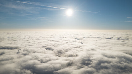 plane window view of midday sun and clouds