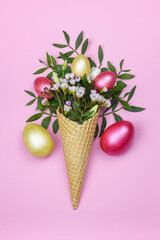 Easter eggs in the waffle cone with spring flowers on pink background.