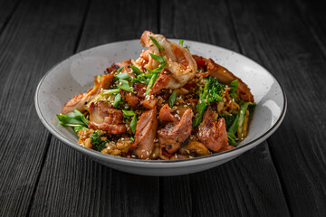 A plate of delicious rice with beef, shrimp and vegetables: carrots, sweet peppers, greens, spices and sauce on a black background