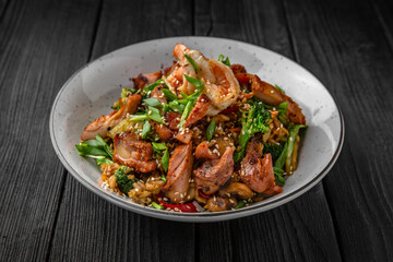 A plate of delicious rice with beef, shrimp and vegetables: carrots, sweet peppers, greens, spices and sauce on a black background