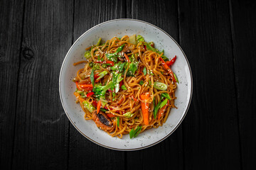 Soba Noodles with vegetables: carrots, sweet peppers, broccoli on a black background. Sushi menu. Japanese food