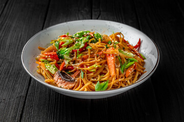 Soba Noodles with vegetables: carrots, sweet peppers, broccoli on a black background. Sushi menu. Japanese food