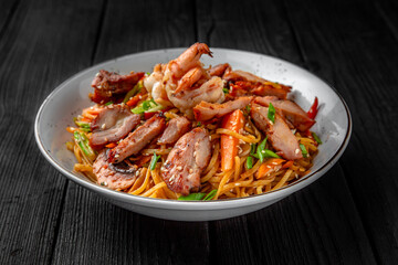 Soba Noodles with chicken, shrimp, mushrooms and vegetables: carrots, sweet peppers, broccoli on a black background. Sushi menu. Japanese food