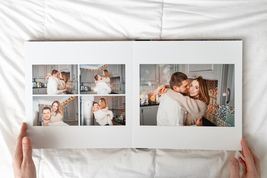 a hands with a book with photos of couple at home on a white background.
