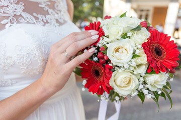 Bouquet of red and a white roses in the bride's hands. Close-up