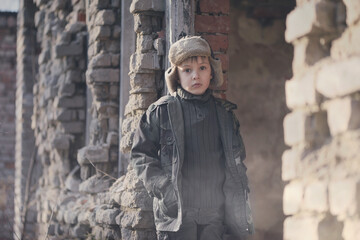 War and the child. Little scared boy in the ruins of the house. Portrait of a poor child, victim of the war.

