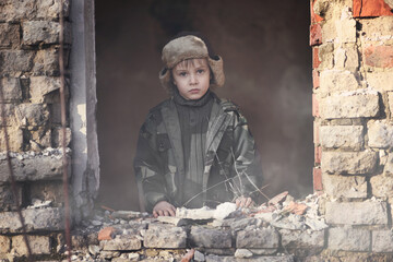 War and the child. Little scared boy in the ruins of the house. Portrait of a poor child, victim of the war.

