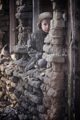 Child and war. Little, poor boy in the ruins of a bombed house.