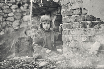 War and the child. Little scared boy in the ruins of the house.

