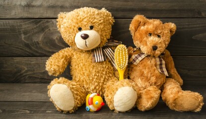Fluffy teddy bears sit on a wooden table with a children's comb and a small rubber duck.  The concept of children's hygiene and cleanliness.  Banner, decorative card, background image, close-up front 