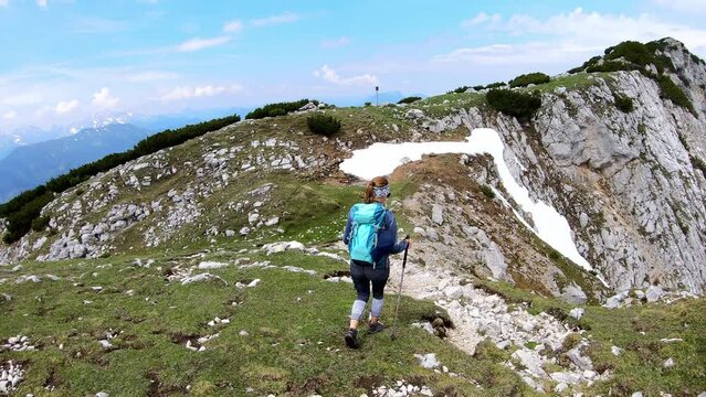 Hiker woman with backpack at summit of Hochpetzen (Peca) with scenic view on mountain peaks in Karawanks and Julian Alps, Carinthia, Austria. Border with Slovenia. Triglav National Park. Goal seeking
