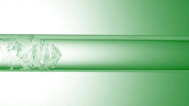 Glycerine is pouring in glass tube with transparent fluid on green background | Abstract skin care cosmetics formulation concept