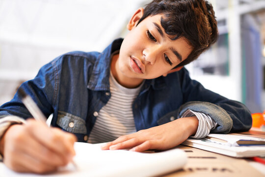 Hes one dedicated kid. Image of a young boy doing his homework.