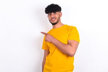 young arab man wearing yellow T-shirt over white background Pointing aside worried and nervous with...