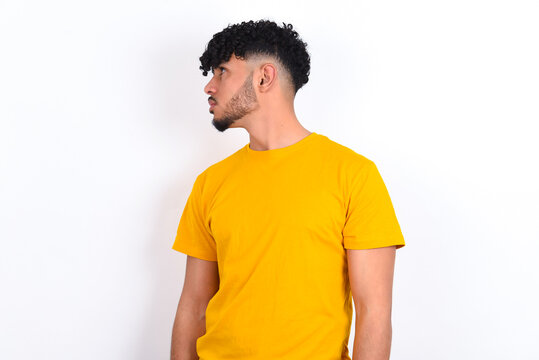 Close Up Side Profile Photo Young Arab Man Wearing Yellow T-shirt Over White Background Not Smiling Attentive Listen Concentrated