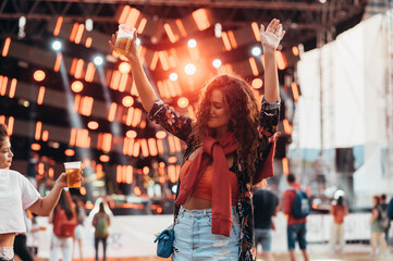 Two beautiful friends drinking beer and having fun on a music festival