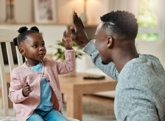 Youve got it. Cropped shot of an adorable little girl high fiving her dad in the living room at home.