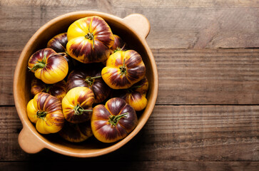 Sart Roloise tomatoes in a clay bowl on a wooden background. Top view and copy space. 