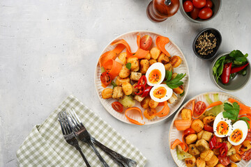 Sweet potato gnocchi with teriyaki tofu with indonesian vegetable salad gado gado - carrots, cucumbers, tomatoes, coriander, sesame seeds, boiled eggs and peanut butter dressing on a white plate