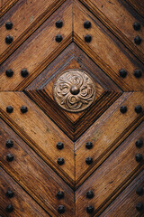 Old wooden dark brown door with diamond-shaped pattern in the rays of daylight. Vintage background