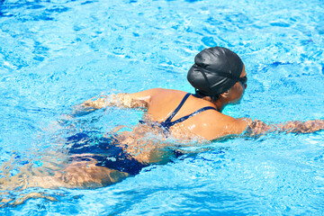 Taking her swimming seriously. Female swimmer making her way through a swimming pool stroke by stroke.