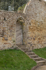 Fototapeta na wymiar Arched doorway in a old stone wall with wooden gate