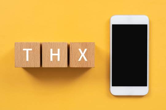 「THK」と書かれた積み木とスマホ