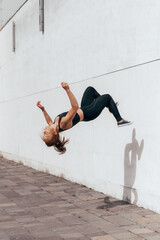 Girl doing parkour backflip on the urban place. Sport lifestyle women doing acrobat trick in the...