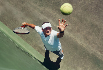 Reach for the sky. High angle shot of a focused middle aged man playing tennis while about to serve...
