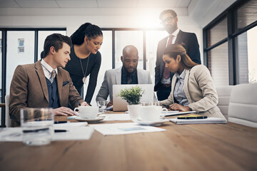 This is what our competitors are looking like. Shot of a group of young businesspeople using a laptop together during a meeting in a modern office.