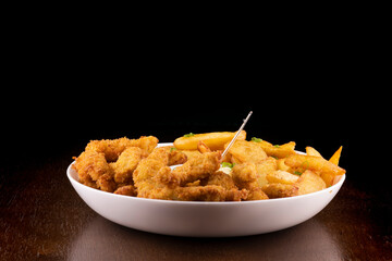 portion of Fish and chips - irish dish on wooden table and dark background