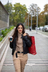 Beautiful woman enjoying in shopping.  with bags and disposable coffee cup walking on sidewalk.Portrait of smiling young student holding shopping bags.
