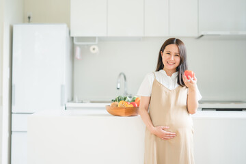 キッチンで野菜を持つ妊婦
