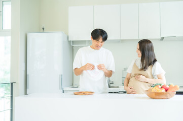 家事を手伝う男性と妊婦（皿洗い）
