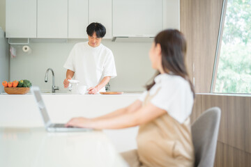 Obraz premium テレワークする妊婦と家事をする男性 