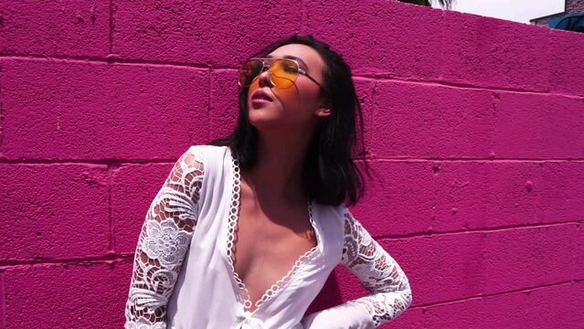 Young Asian American Female Fashion Model Posing to Camera in Front of Pink Wall
