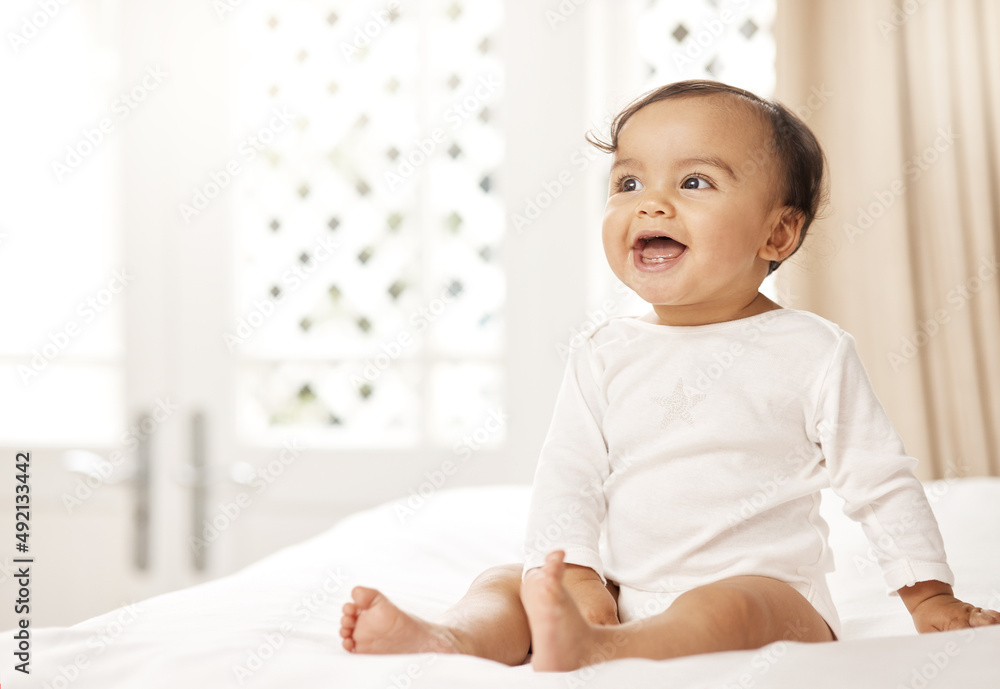 Canvas Prints She has the cutest smile. Shot of an adorable baby girl sitting on a bed.