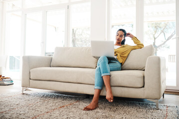 Obraz premium Im proud of how far Ive come with this blog. Full length shot of an attractive young businesswoman sitting on her couch and blogging from her laptop while at home.