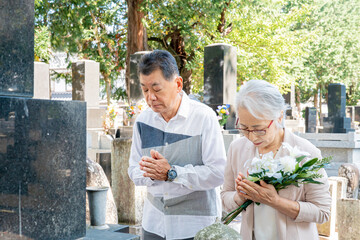 お墓参りする高齢者の男女（仏花）
