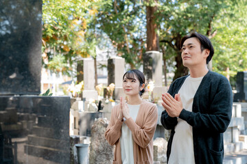 お墓参りする男女（合掌）
