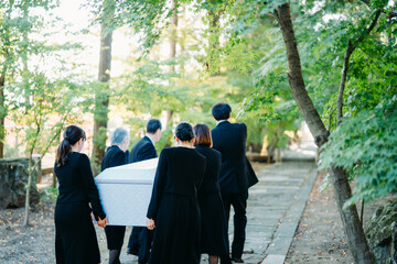 お葬式で棺桶を運ぶ遺族
